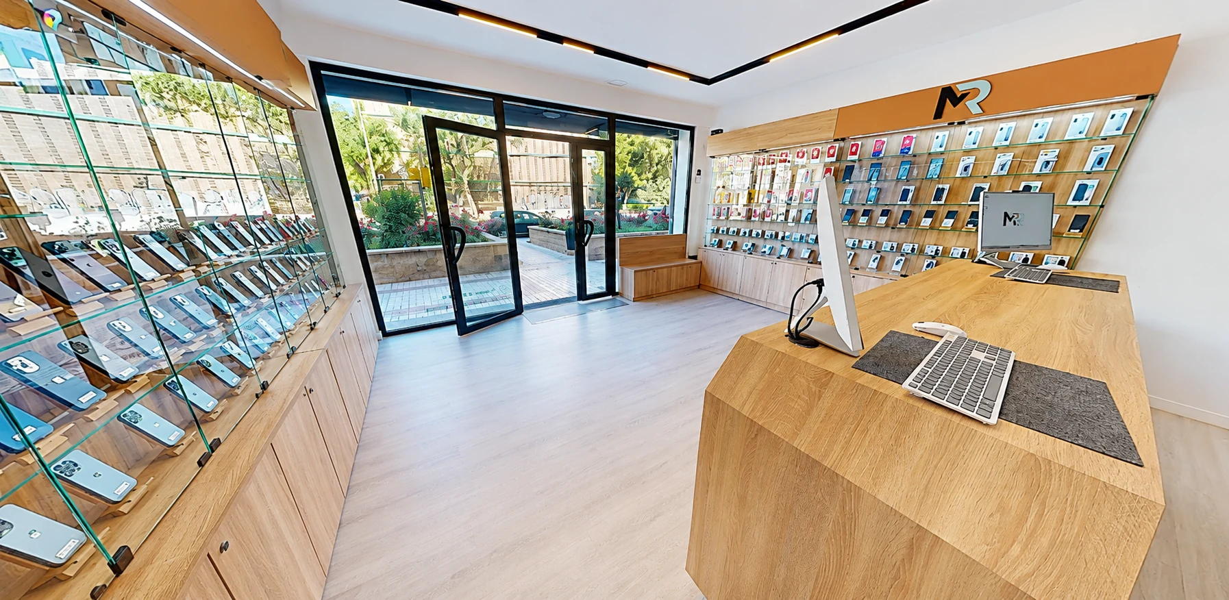 Interior de la tienda Manzana Reparada en Málaga: mostrador con iMac y exposición de móviles